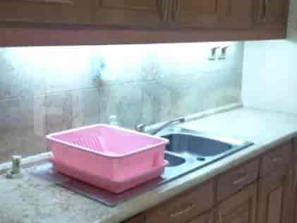 A kitchen counter with a double sink, a pink dish drying rack, and wooden cabinets.