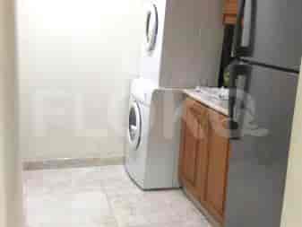A laundry area with stacked washing machine and dryer, a refrigerator, and wooden cabinets.