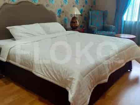 A bedroom featuring a large bed with white bedding, a patterned wallpaper, and a blue armchair.
