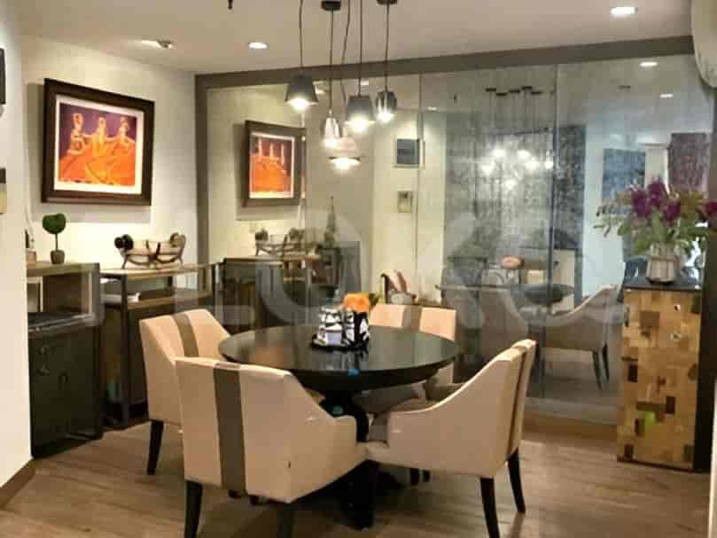 A dining room with a round table and chairs, surrounded by mirrored walls.