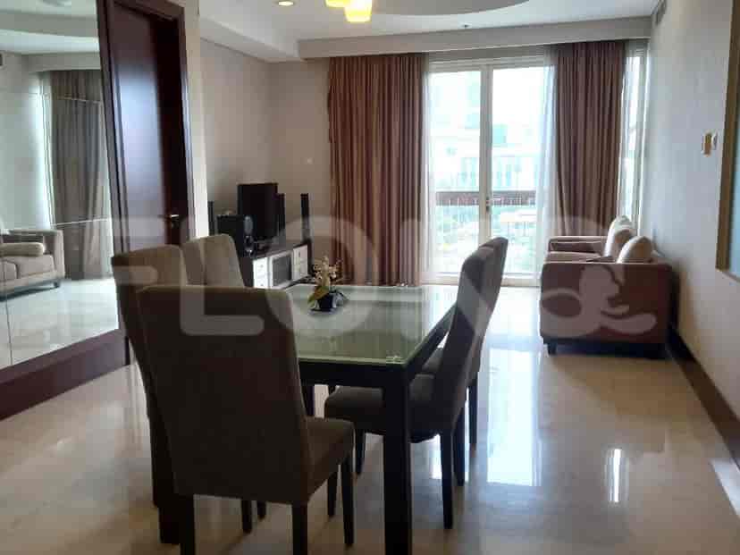 A living room area with a dining table, sofa, and large windows.