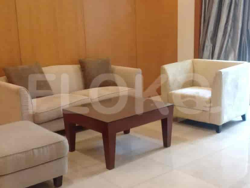 A cozy living room with a beige sofa, armchair, ottoman, and a coffee table.