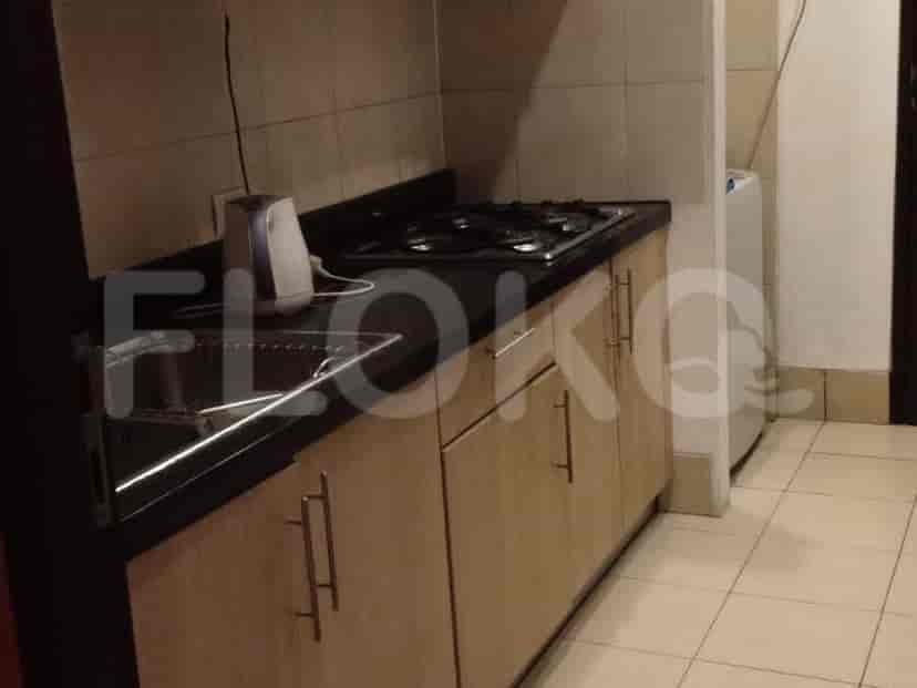 A compact kitchen with wooden cabinets, a black countertop, sink, and a gas stove.