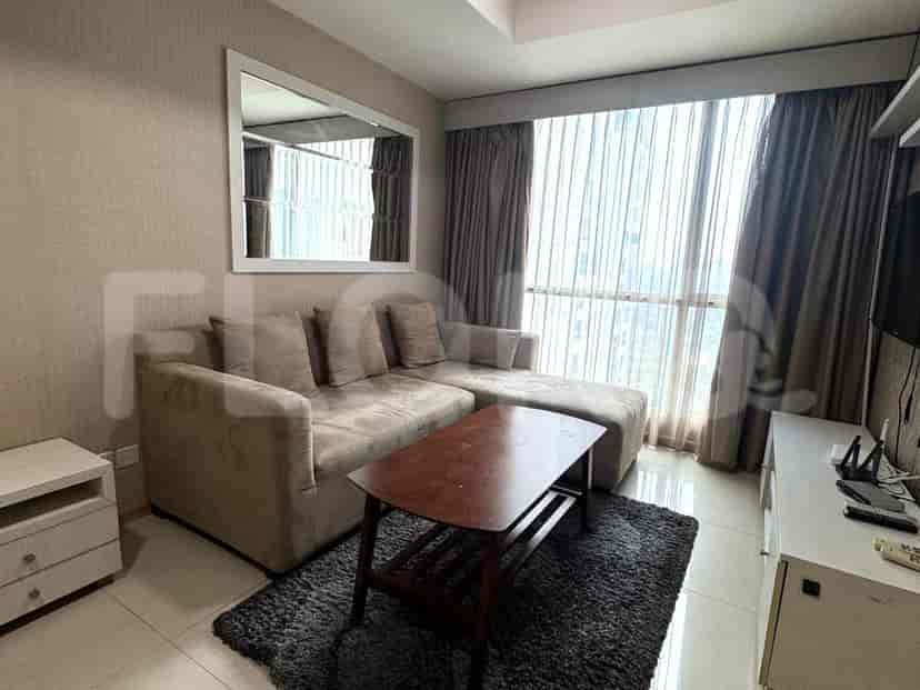 A modern living room featuring a sectional sofa, a coffee table on a rug, and a large window with curtains.