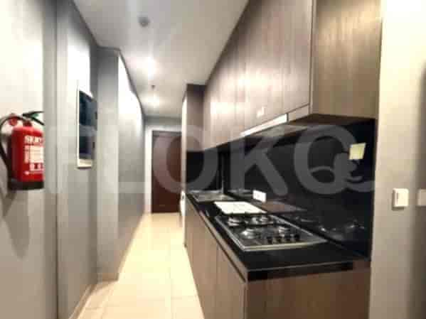 A linear kitchen with dark wood cabinets, a black countertop, and a gas stove.