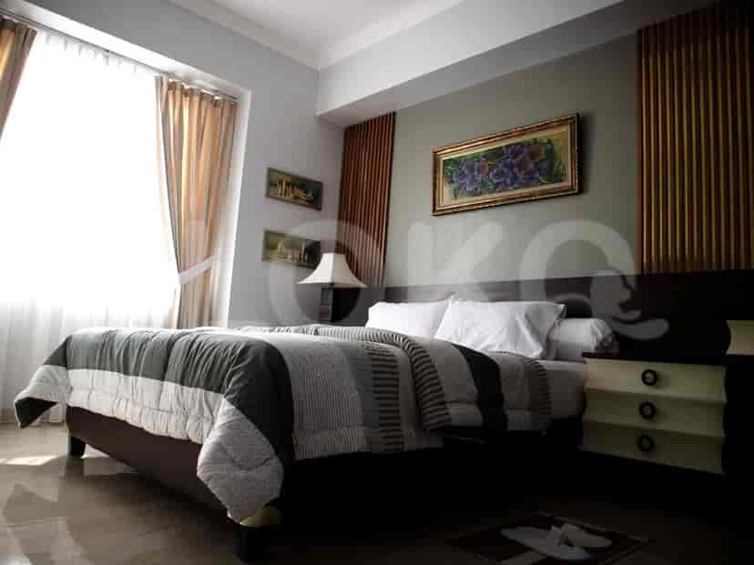 A cozy bedroom with a queen-sized bed, soft curtains, and a framed artwork above the headboard.