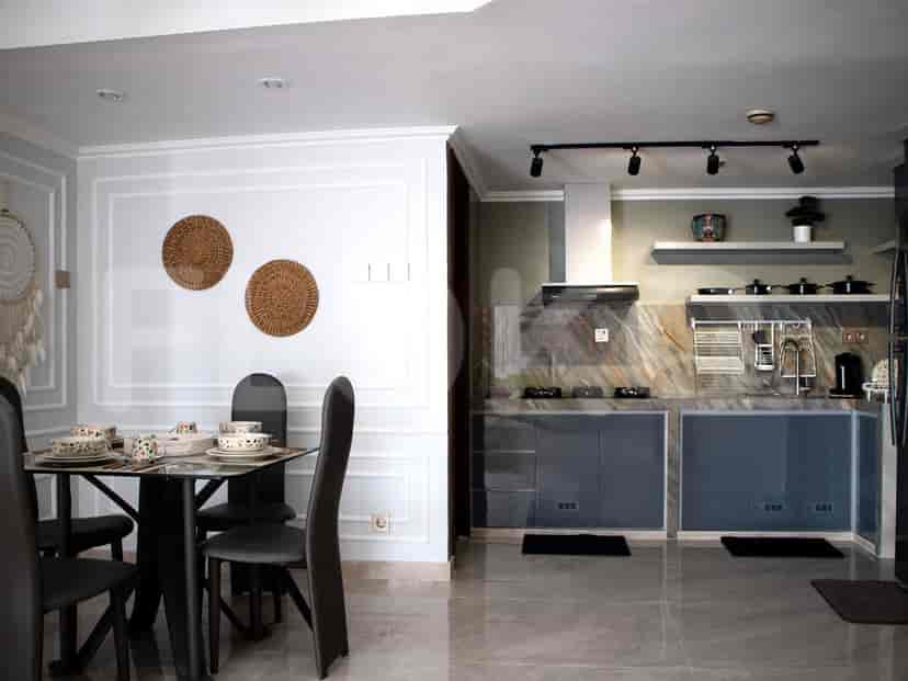 A combined kitchen and dining area with a glass-top dining table and a modern kitchen setup.