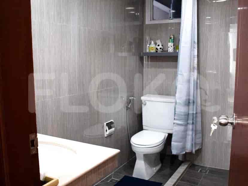 A modern bathroom with grey tiled walls, a white toilet, and a shower area with a curtain.