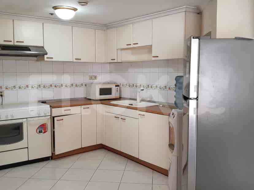 A kitchen with white cabinets, a gas stove, microwave, refrigerator, and a water dispenser.
