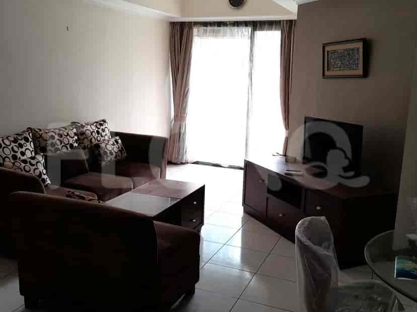 A living room with a brown sofa, coffee table, and TV stand with a TV.