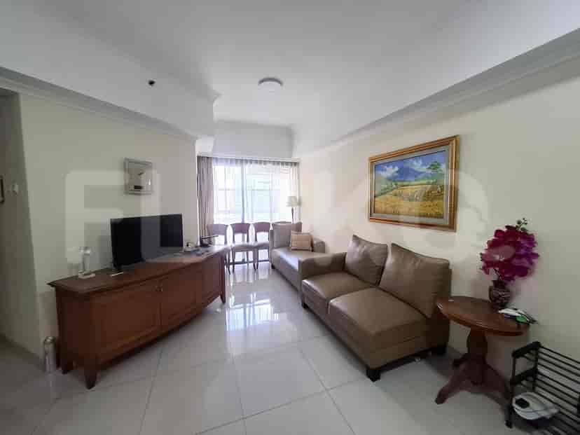 A living room with a sectional sofa, a TV stand with a TV, and a large window.