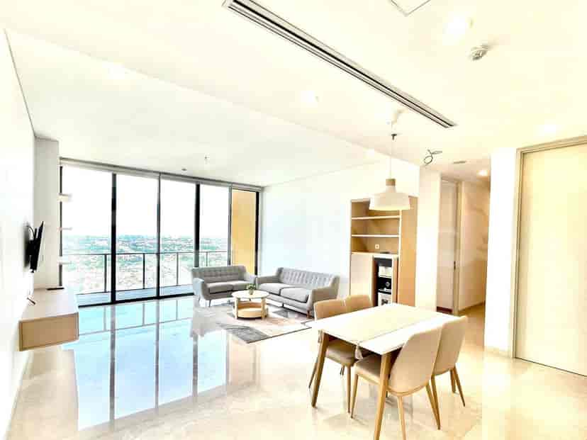 Ruang tamu modern dengan jendela besar yang menawarkan pemandangan kota, sofa abu-abu, dan area makan.