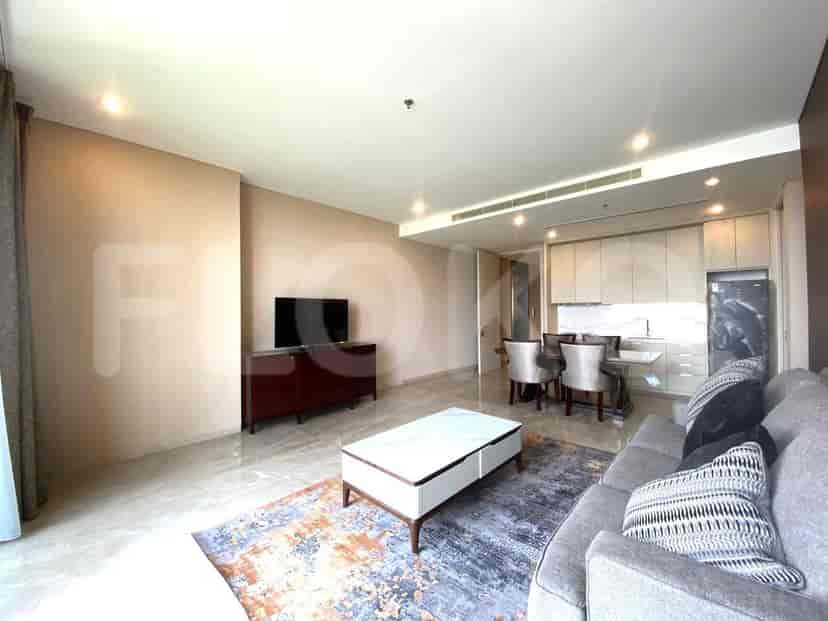 Area ruang tamu dan ruang makan modern dengan sofa abu-abu, meja kopi, set makan, dan dapur terbuka.