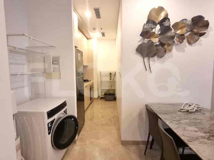 Area dapur kecil dengan peralatan modern, bersebelahan dengan ruang binatu dengan mesin cuci.