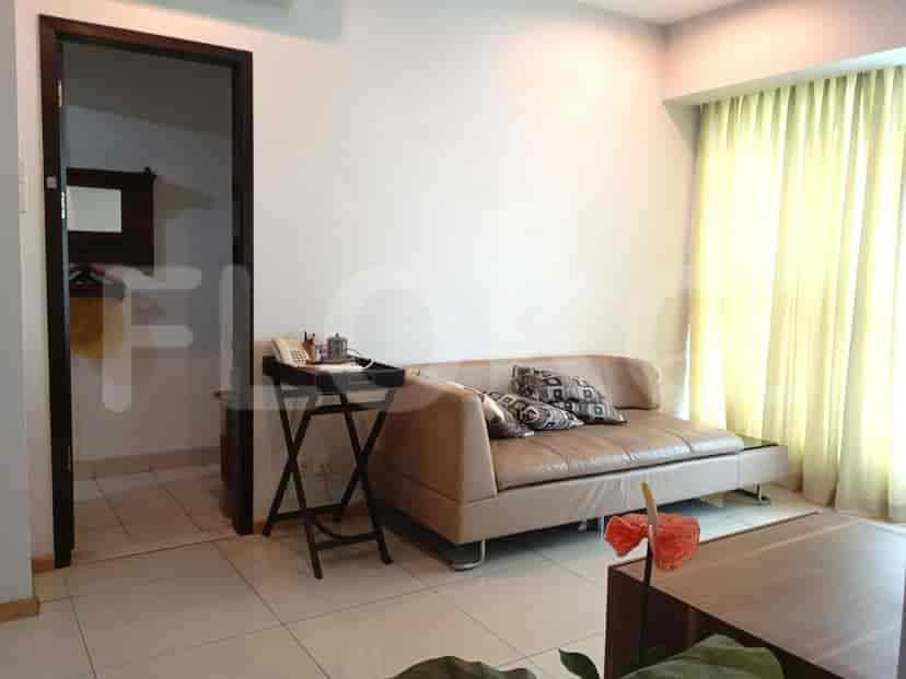 A living room with a beige sofa, a side table with a phone, and a large window with curtains.