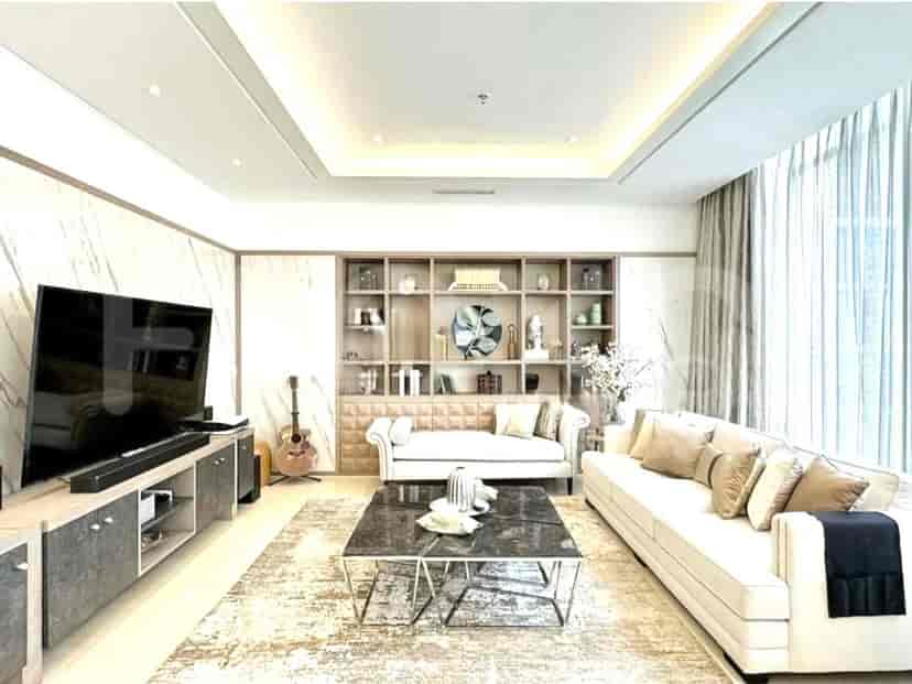 A spacious living room with a sectional sofa, entertainment unit with a large TV, and a marble coffee table.
