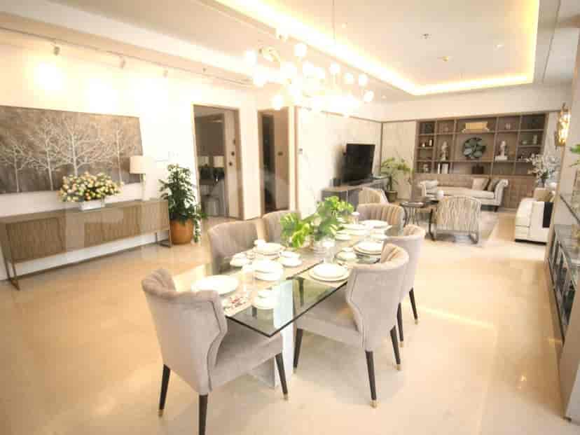 A formal dining room with a glass-top table, upholstered chairs, and a credenza.