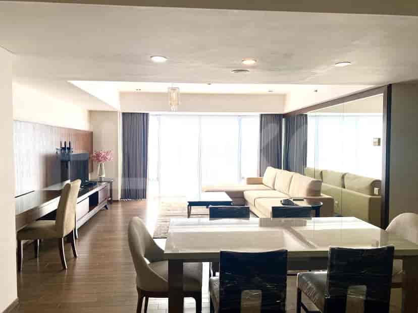 A combined living and dining area with a sectional sofa, dining table, and large windows.