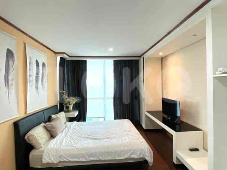 A bedroom with a queen-size bed, large window with dark curtains, and a bedside table.