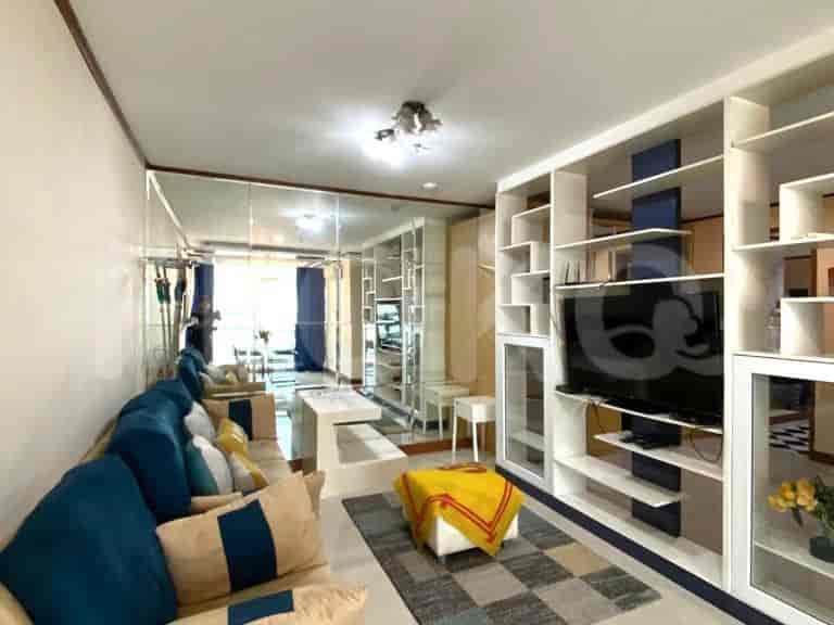 A spacious living room with a sectional sofa, large mirrored wall, entertainment unit with a TV, and a coffee table.