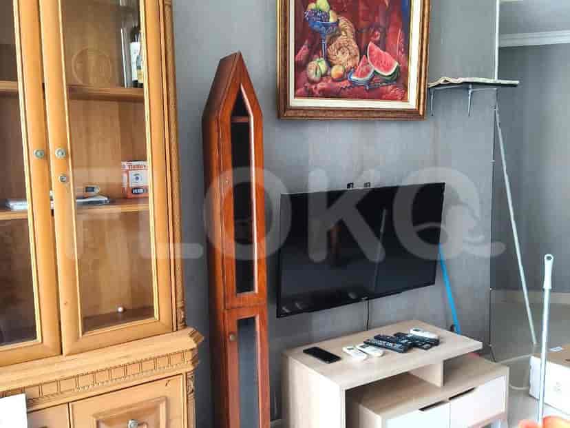 Living room with wooden cabinet, tall wooden display cabinet, painting, and a TV on a stand.
