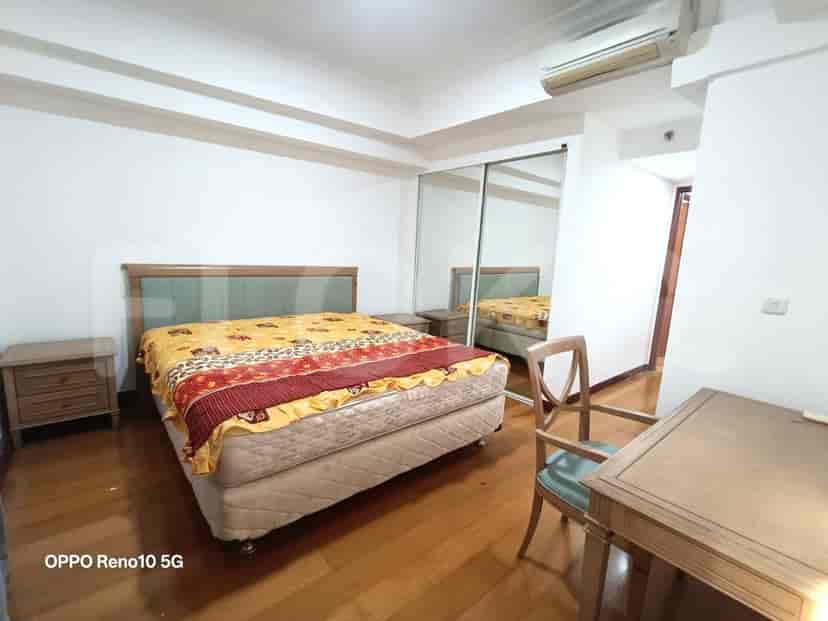 A bedroom with a queen-size bed, nightstands, a wooden chair, and a mirrored closet.