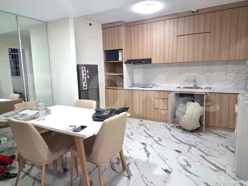 Sebuah dapur dengan lemari kayu, kulkas, microwave, dan meja makan dengan kursi.