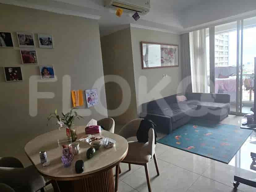 A combined living and dining area with a round dining table, a sofa, a rug, and a large balcony door.