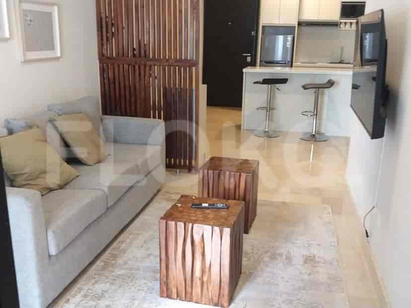 A compact living room with a grey sofa, two wooden cube side tables, and a view of a kitchenette.