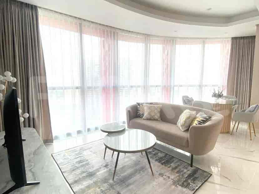 A modern living room with a curved sofa, round coffee tables, and sheer curtains.