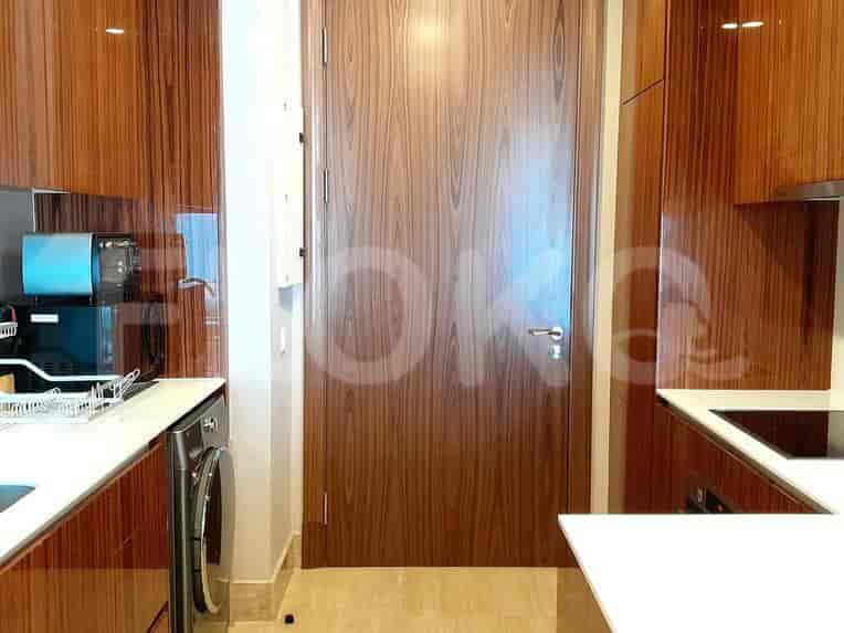 A modern kitchen with wood cabinets, white countertops, and integrated appliances.