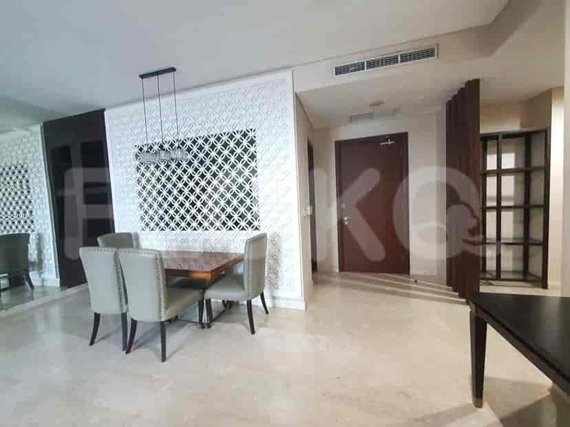 A dining area with a wooden table and chairs, separated by a decorative screen.