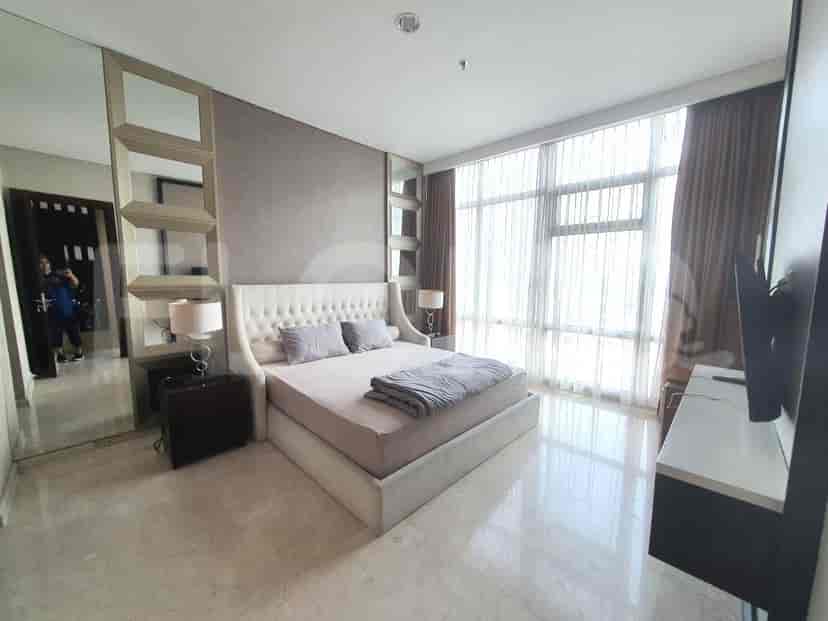 A luxurious bedroom with a king-size bed, large window with sheer curtains, and a dresser with a TV.