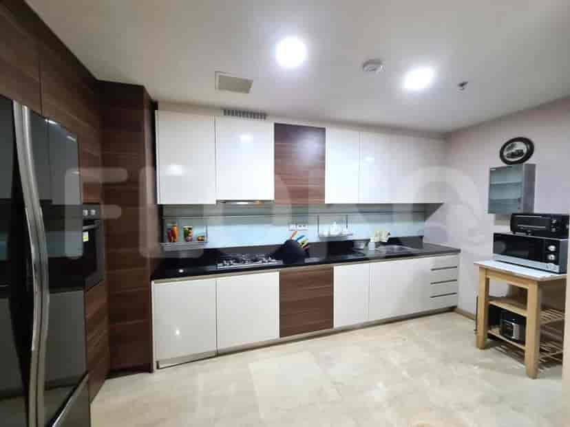 A modern kitchen with white and wood cabinets, a gas stove, and a stainless steel refrigerator.