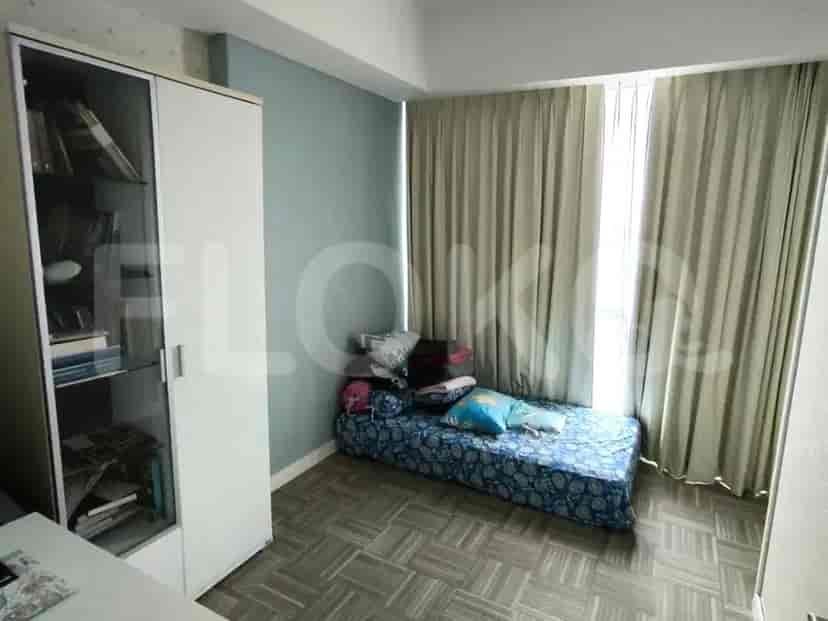 Kamar tidur kecil atau area belajar dengan tempat tidur tunggal dan lemari berkaca.