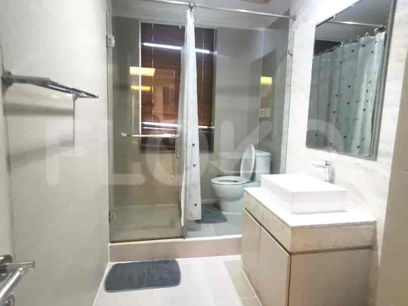 A modern bathroom with a glass-enclosed shower, a white sink, and a toilet.