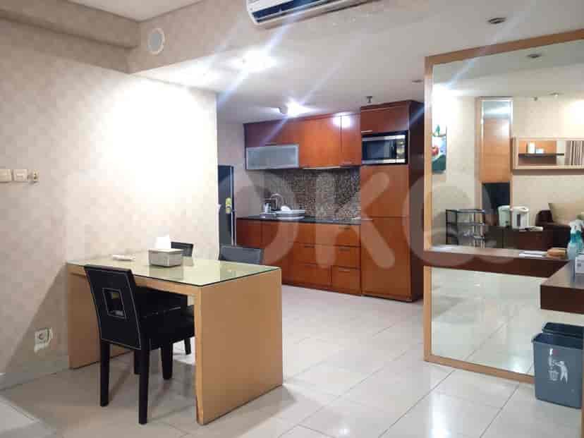 Kombinasi dapur dan ruang makan dengan lemari kayu, meja makan, dan cermin besar.