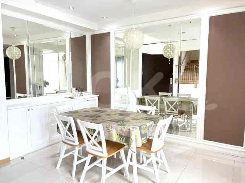A dining room with a table set for four, surrounded by chairs, and large mirrored walls.