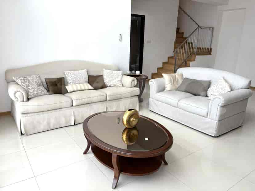 A living room with a large sofa, a love seat, and a coffee table in front of a staircase.