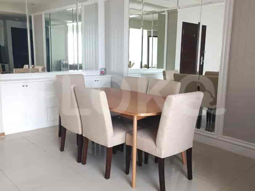 A dining room with a wooden table, upholstered chairs, and mirrored cabinets.