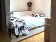 Kamar tidur dengan tempat tidur tanam, sprei kotak-kotak, dan vas bunga.