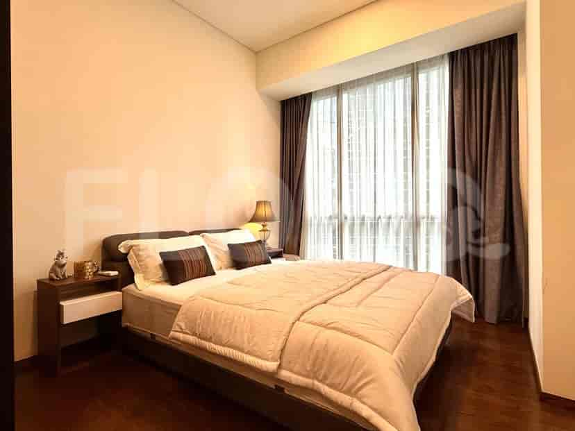 A bedroom with a bed, bedside table, and large windows.