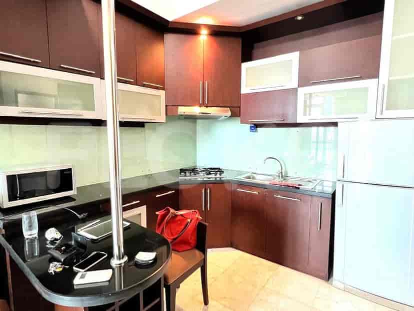 A compact kitchen with dark wood cabinets, a refrigerator, and a small island.