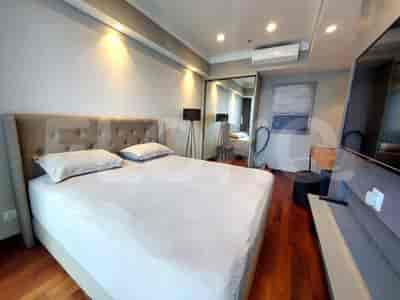Sebuah kamar tidur dengan tempat tidur besar, lemari pakaian cermin, dan televisi.