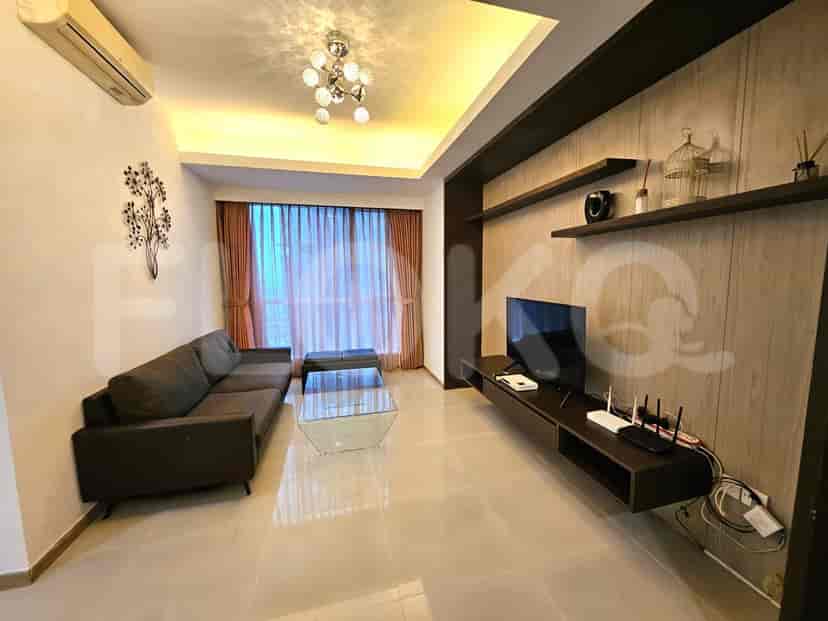 A modern living room featuring a grey sofa, glass coffee table, and a wall-mounted TV with shelving.
