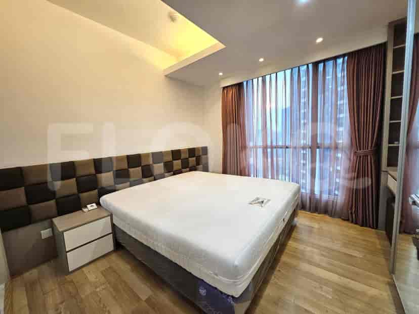 A bedroom with a king-size bed, a modern headboard, and large windows with curtains.