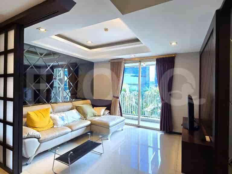 A modern living room featuring a sectional sofa, a glass coffee table, decorative mirrors, and large sliding doors leading to a balcony.