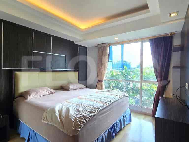 A cozy bedroom with a large bed, wood-paneled accent wall, and a large window with curtains.
