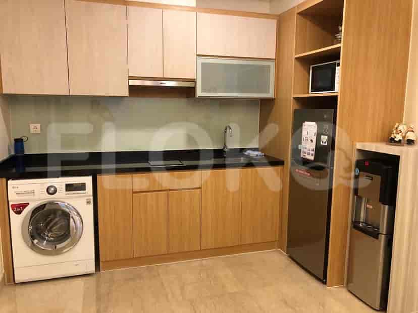 A modern kitchen with wooden cabinets, a stainless steel refrigerator, and a washing machine.