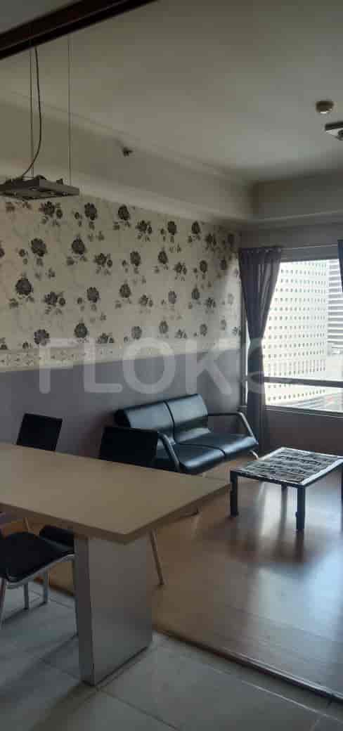 A living room with a sofa, dining table, and large windows.